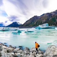 The ubiquitous Colin Moneath picks his way through this panorama of bergs along the rugged shoreline of Tasman Lake, (Mt Cook's Caroline face upper left), Aoraki / Mount Cook National Park, UNESCO World Heritage Site.