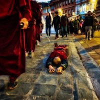 Tibetan nun prostrates the kora, at Boudanath Stupa - dusk.