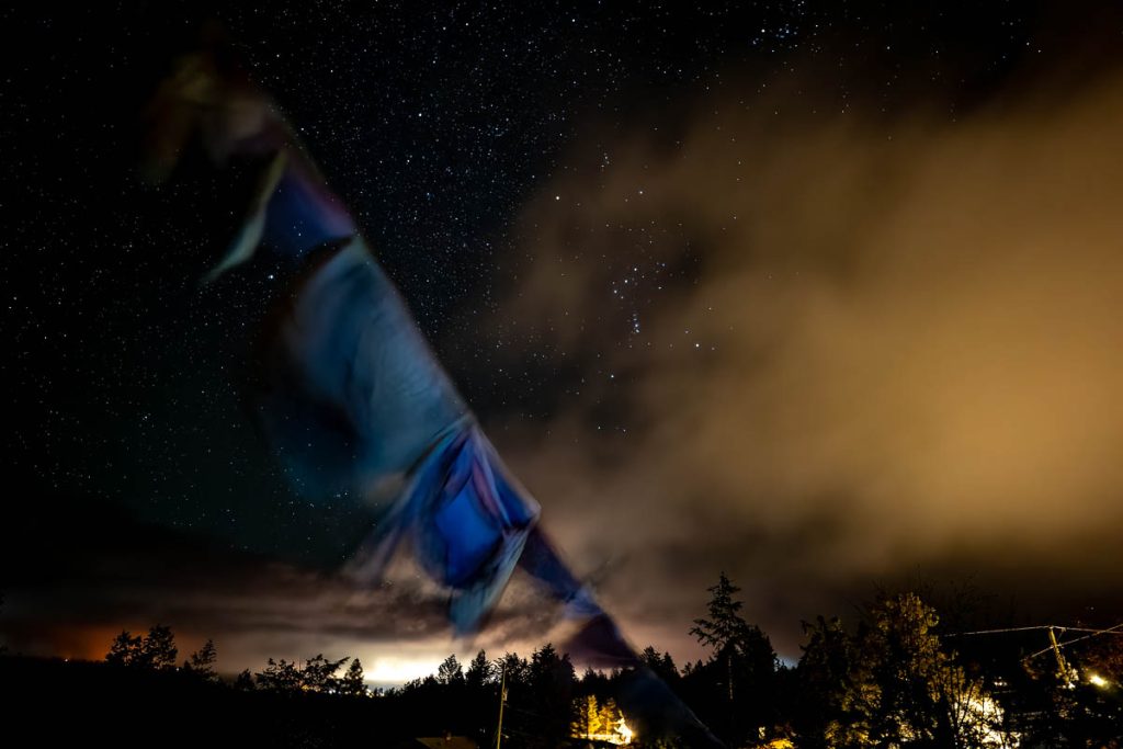 Prayer flags framed by stars and light pollution. © Pat Morrow 2022