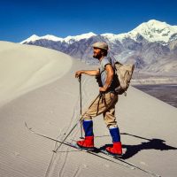 Pat Morrow climbs up 300 m high dunes on telly skis with 7500m Kongur in background, on completion of ski expedition to Mt Muztagata in the Chinese Pamir with Stephen Bezruchka, John Amatt, and photo by Lloyd Gallager, 1981